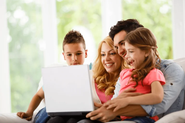 Family sitting together and browsing Kerala tour packages on a travel website using a laptop while planning a vacation.