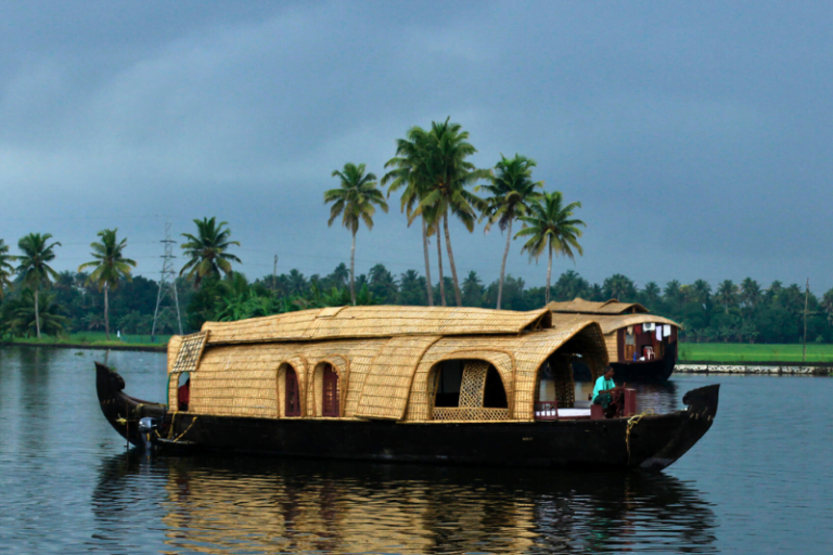 Bamboo-crafted traditional houseboat sailing through Kerala backwaters surrounded by calm water and greenery.